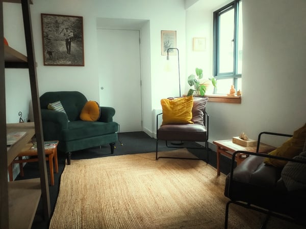 Frameshift Counselling practice at Flour Mill Dundee. A windowed room with an armchair, two comfy chairs, a rug, a table and some plants.